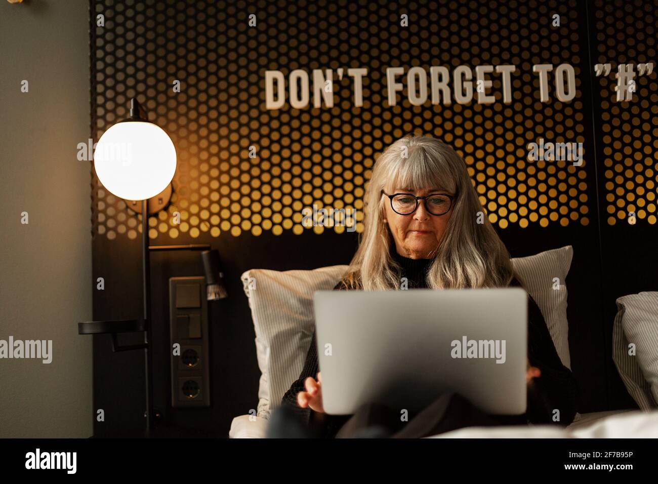 Woman using laptop in hotel bed Stock Photo