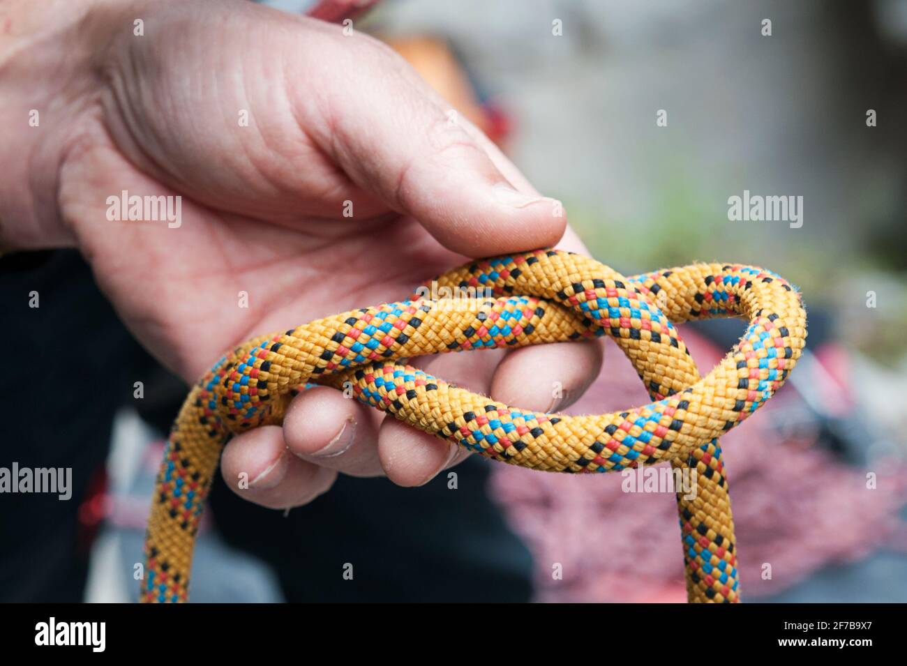 Man's hand making a correct safety knot on a strong colorful rope