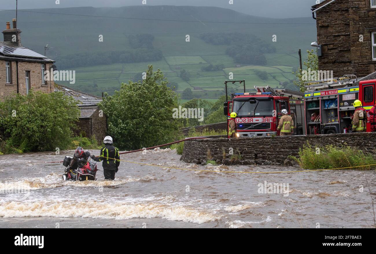 Motorcyclist being rescued from a flooded river at Gayle, Hawes in North Yorkshire, by fire service and Swaledale Mountain Rescue crews. North Yorkshi Stock Photo