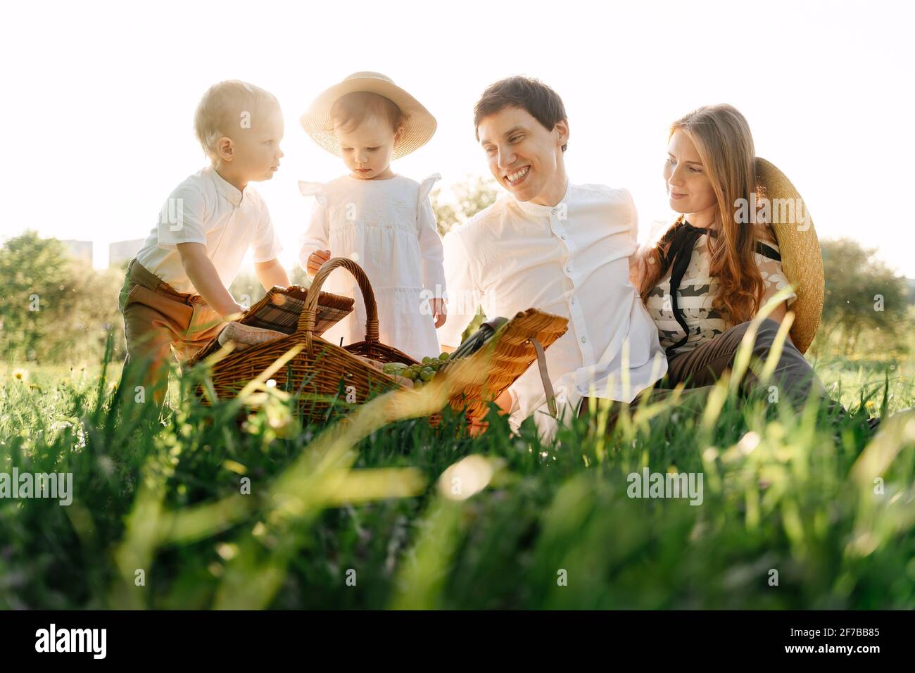 Happy family with children in nature in the summer sits on the grass. Stock Photo
