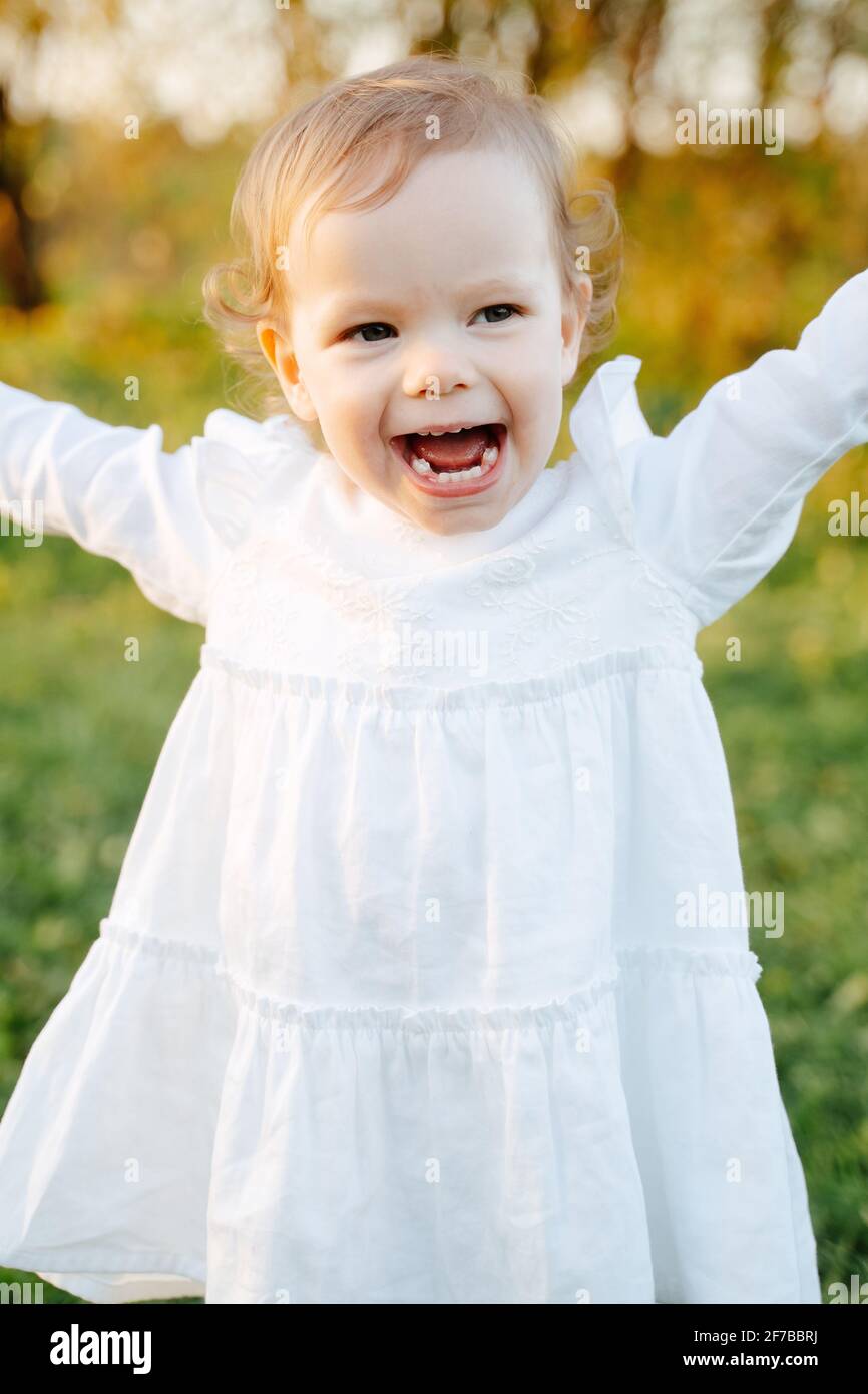 Happy girl in a white dress runs along a green park in summer Stock ...