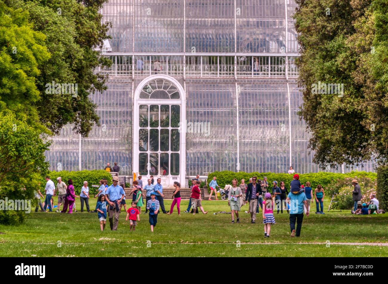 Visitors on the grass in front of the Palm House at Kew Gardens.  Designed by Decimus Burton and finished in 1848. Stock Photo