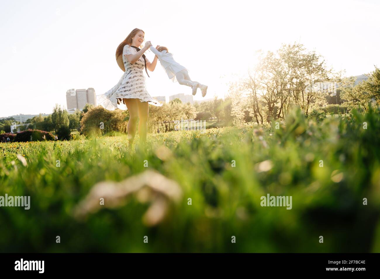 A young mother circles her little daughter in the park for a walk. Stock Photo