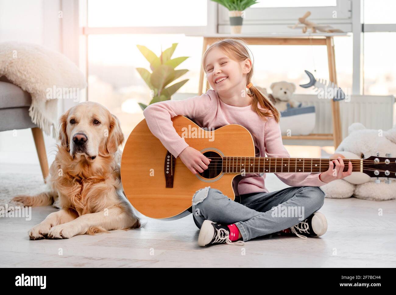 Little girl with guitar and golden retriever dog Stock Photo
