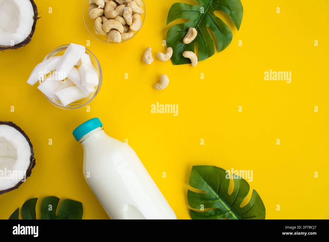 Coconut milk in the glass bottle and cashew nuts on the yellow