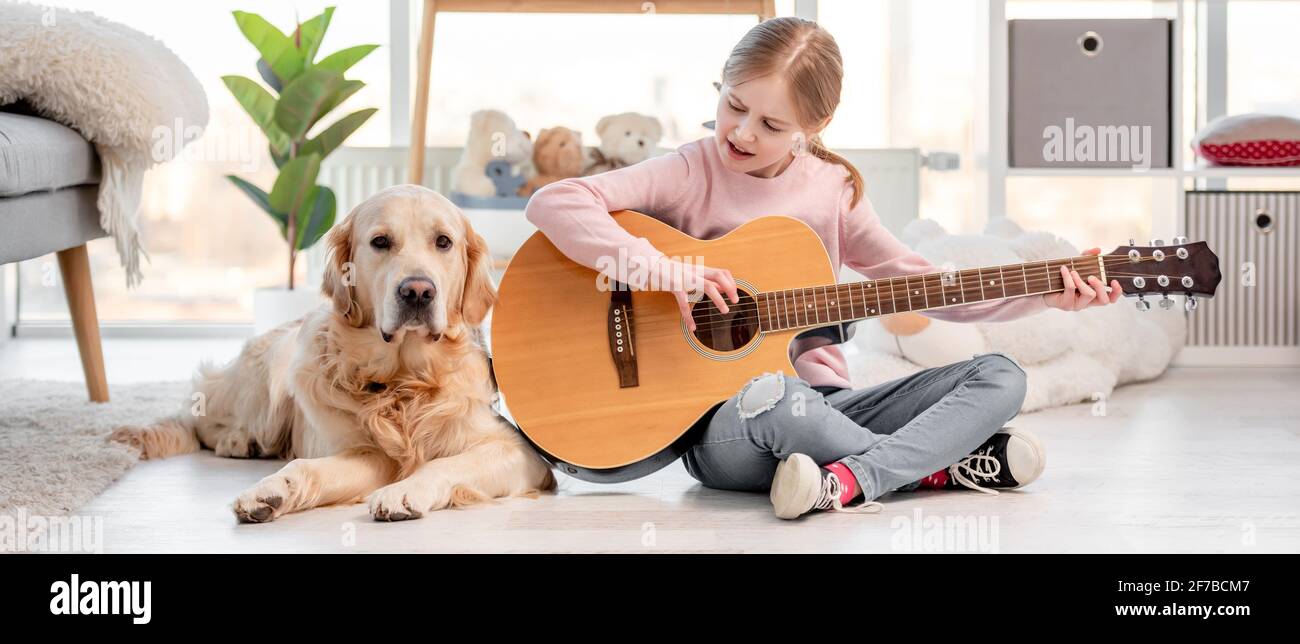 Little girl with guitar and golden retriever dog Stock Photo