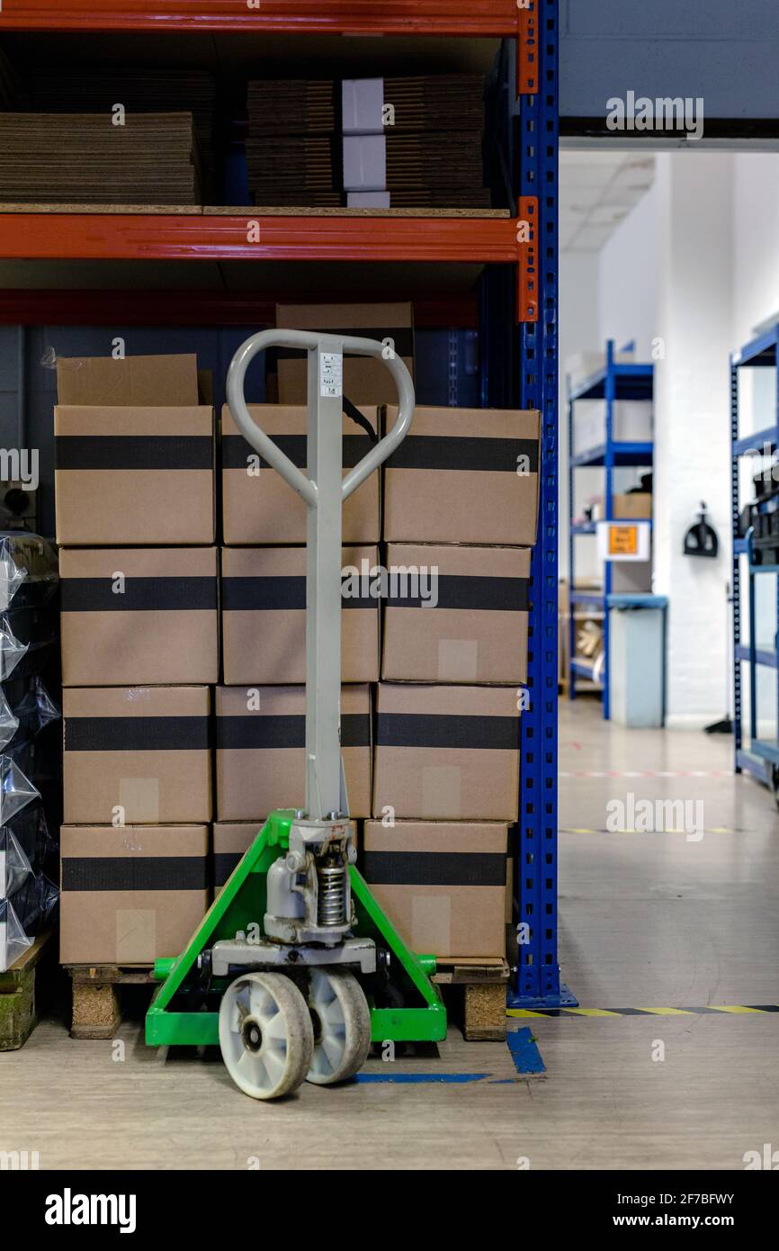 A pallet stacked with boxes ready to be shipped out. A pallet truck is sitting under the pallet to ready move it. Warehouse, despatch, shipping, parce Stock Photo