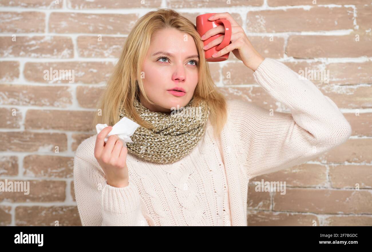 Taking a cure. Cute woman caught terrible cold virus. Sick woman with sore throat drinking cup of warm tea. Pretty girl with nasal cold suffering from Stock Photo
