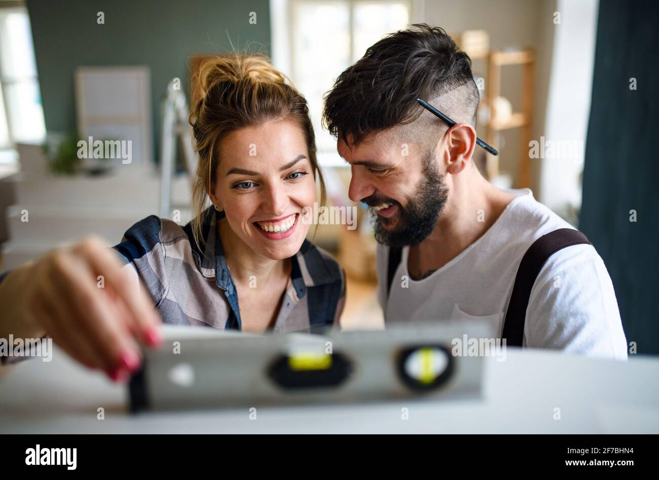 Mid adults couple with leveler indoors at home, relocation and diy concept. Stock Photo