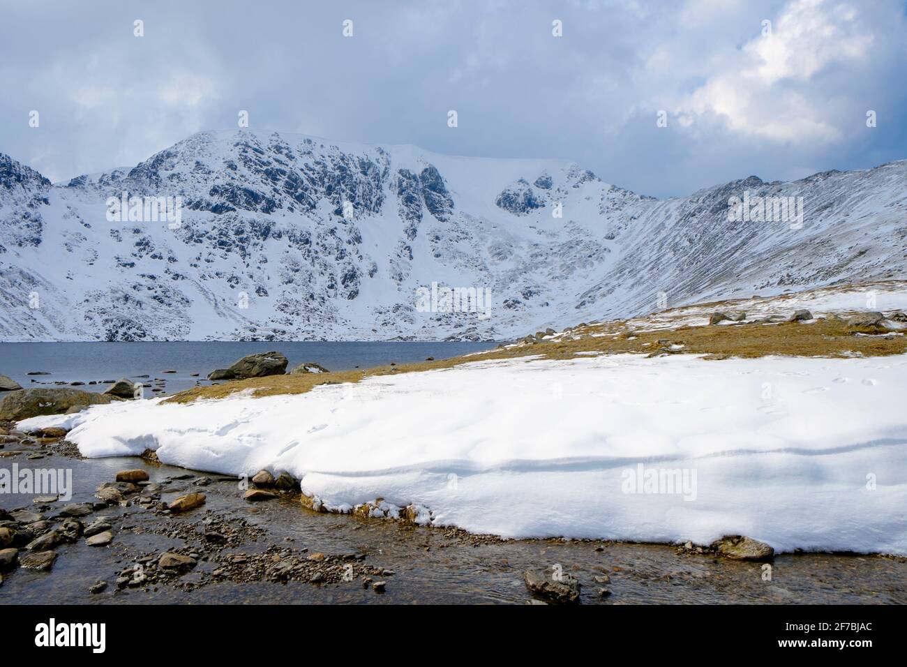 Red Tarn lake and snow covered Helvellyn fell with Swirral Edge in winter in mountains of Lake District National Park, Cumbria, England, UK, Britain Stock Photo