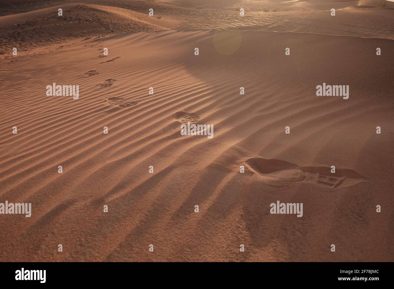 Sunset over the sand dunes with footprints in the desert. The ghost town of Al-Madam is about 60 km from Dubai City. united arab emirates. The concept Stock Photo