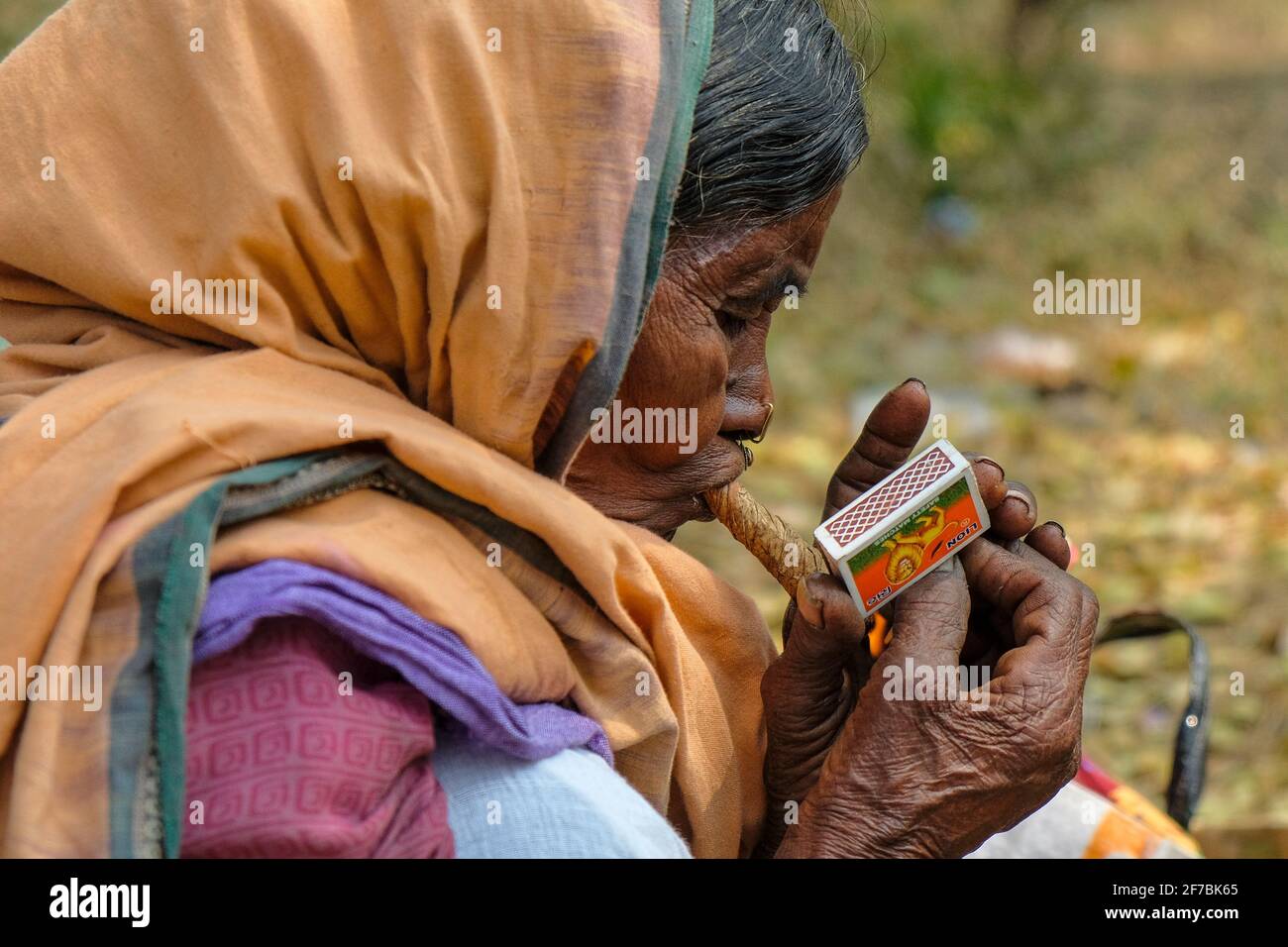 Chatikona, India - February 2021: An Adivasi woman from the Desia Kondh tribe smoking in the Chatikona market on February 17, 2021 in Odisha, India. Stock Photo