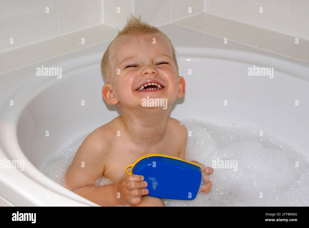 three years old boy sitting in a bathtub Stock Photo