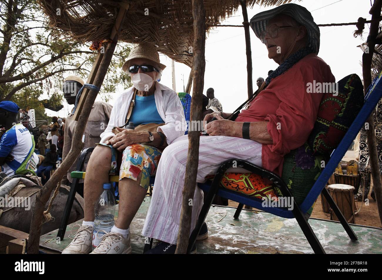 Senior travellers travelling on a donky chart ,one wearing a mask in Mali , West Africa . Stock Photo