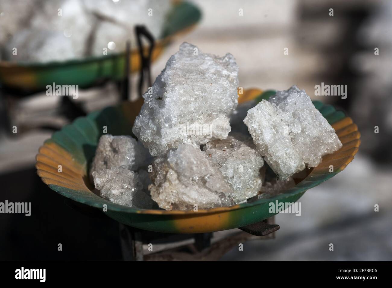 Salt merchant in market where salt is cut up into smaller pieces on