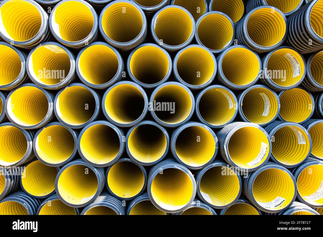Plastic pipes production plant warehouse. Yellow PVC channelled pipes. Stock Photo