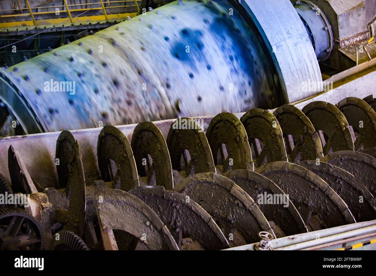 Screw conveyor close-up. Ore concentration plant. Factory ball mill on background. Stock Photo