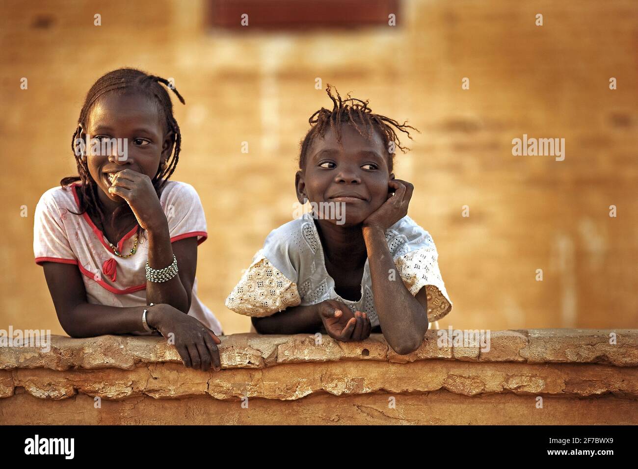 Two girls friends having fun on a wall in the village Niafunke ,Mali, West Africa. Stock Photo