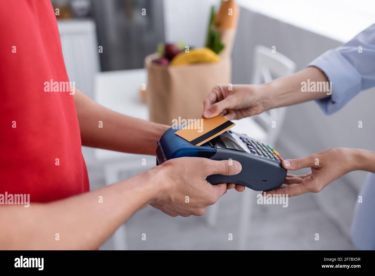 cropped view of courier holding payment terminal near woman with credit card Stock Photo