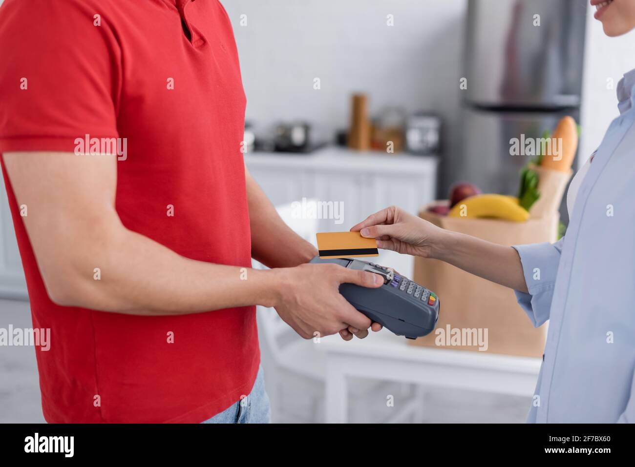 cropped view of woman holding credit card near delivery man with payment terminal Stock Photo