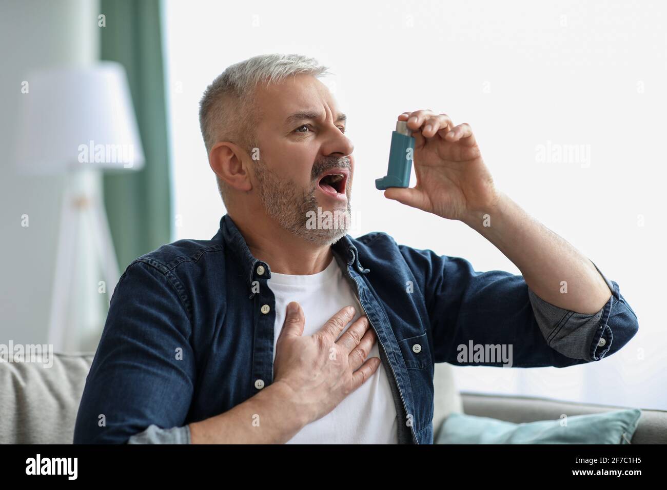 Senior man touching chest and using inhaler Stock Photo