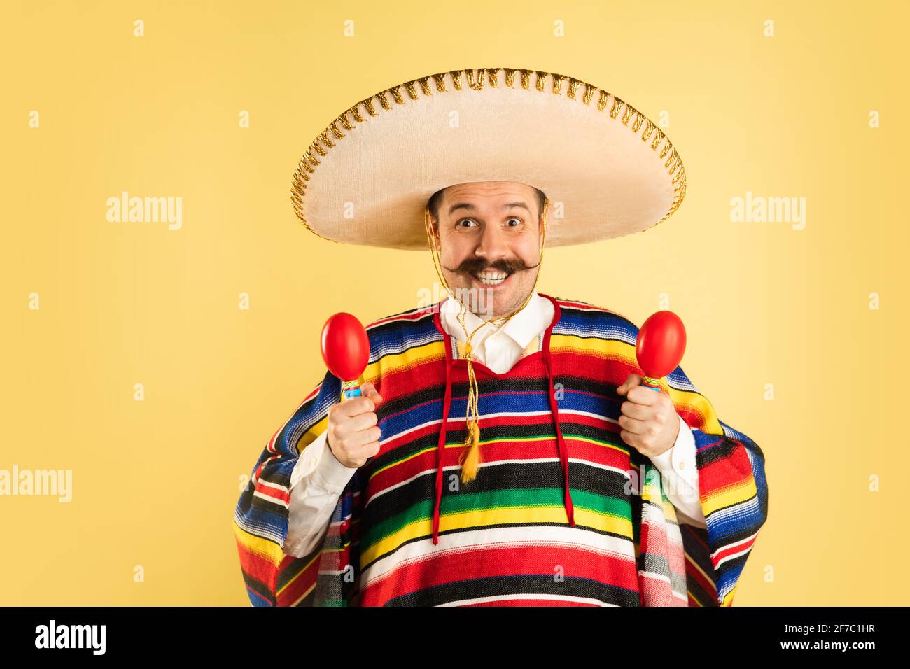 Happy man in sombrero and bright poncho isolated over yellow background  Stock Photo - Alamy