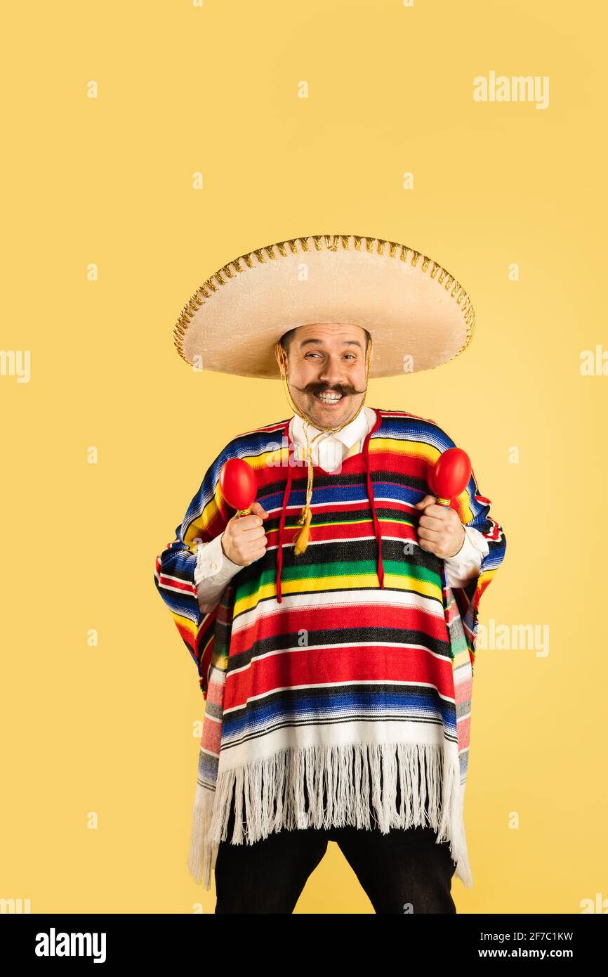 Portrait of man in sombrero and bright poncho isolated over yellow  background Stock Photo - Alamy