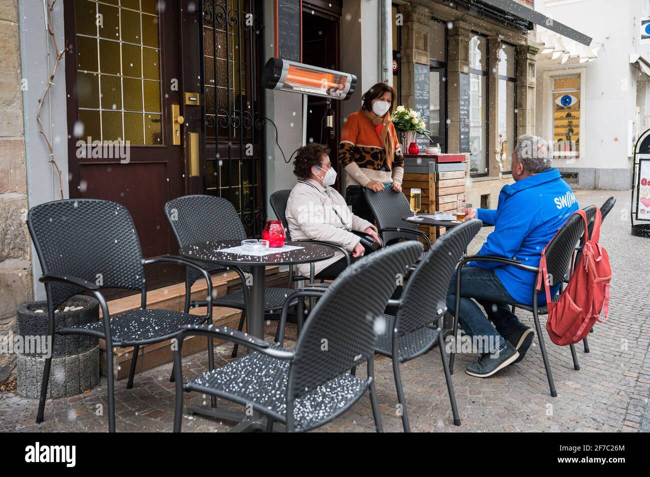 06 April 2021, Saarland, Saarbrücken: Landlady Monika Müller (m) talks to guests sitting in front of her pub 'Glühwürmchen' in the city centre. Since 06.04.2021, restaurateurs have been allowed to reopen their outdoor restaurants under certain conditions within the framework of the Saarland Model. Photo: Oliver Dietze/dpa Stock Photo