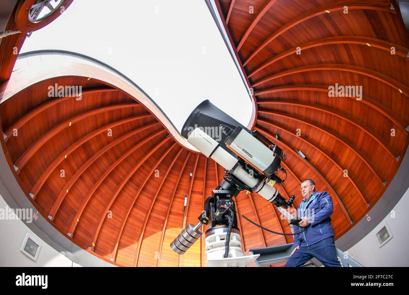 25 March 2021, Saxony, Rodewisch: Olaf Graf, director of the observatory and planetarium, sets up the new combination reflecting telescope, refracting telescope and an astrograph in the historic, rotating wooden dome. Saxony's observatories are making themselves fit for the coming years with investments. In the facility in Rodewisch, which was opened in 1967, a new reflecting telescope with a diameter of 50 centimeters will be the focus of the newly renovated wooden dome. In the GDR, there was a high density of observatories and planetariums, partly due to the compulsory subject of astronomy. Stock Photo