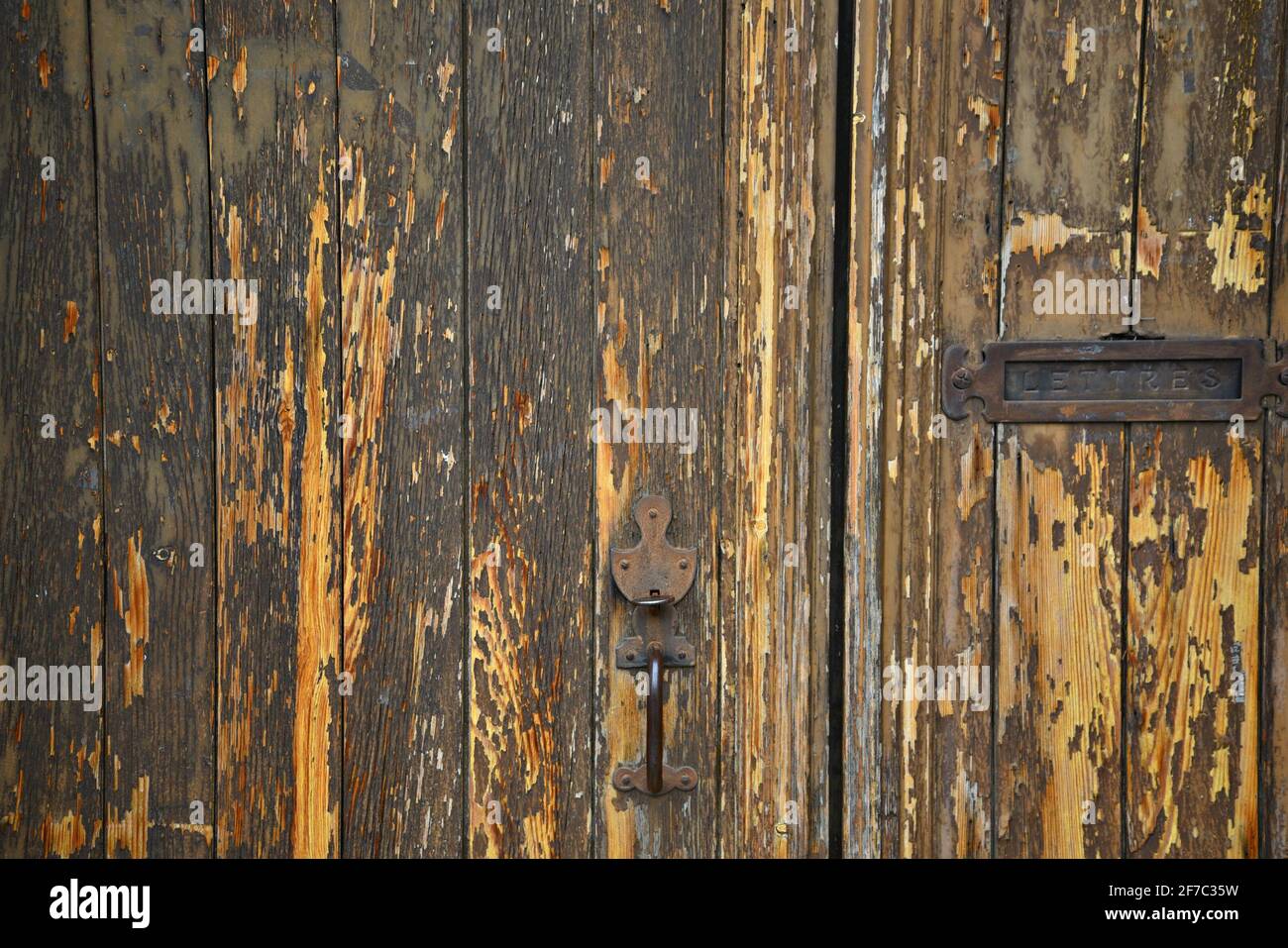 Antique weathered oak door with a rusty letter slot and handle in the picturesque village of Grambois, Provence-Alpes-Côte d'Azur, Vaucluse, France. Stock Photo