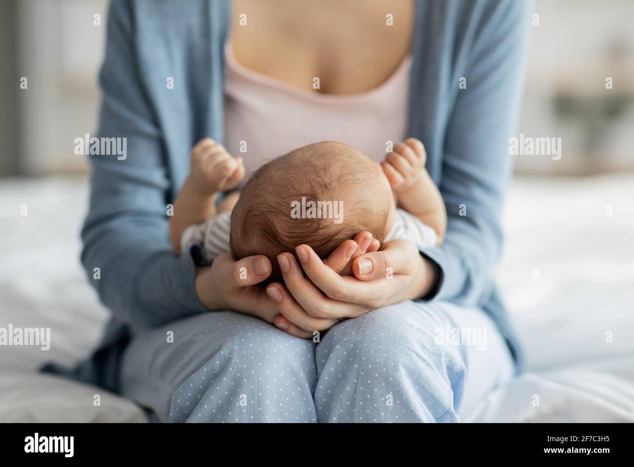Mother Care. Unrecognizable mom holding newborn baby on her laps Stock Photo