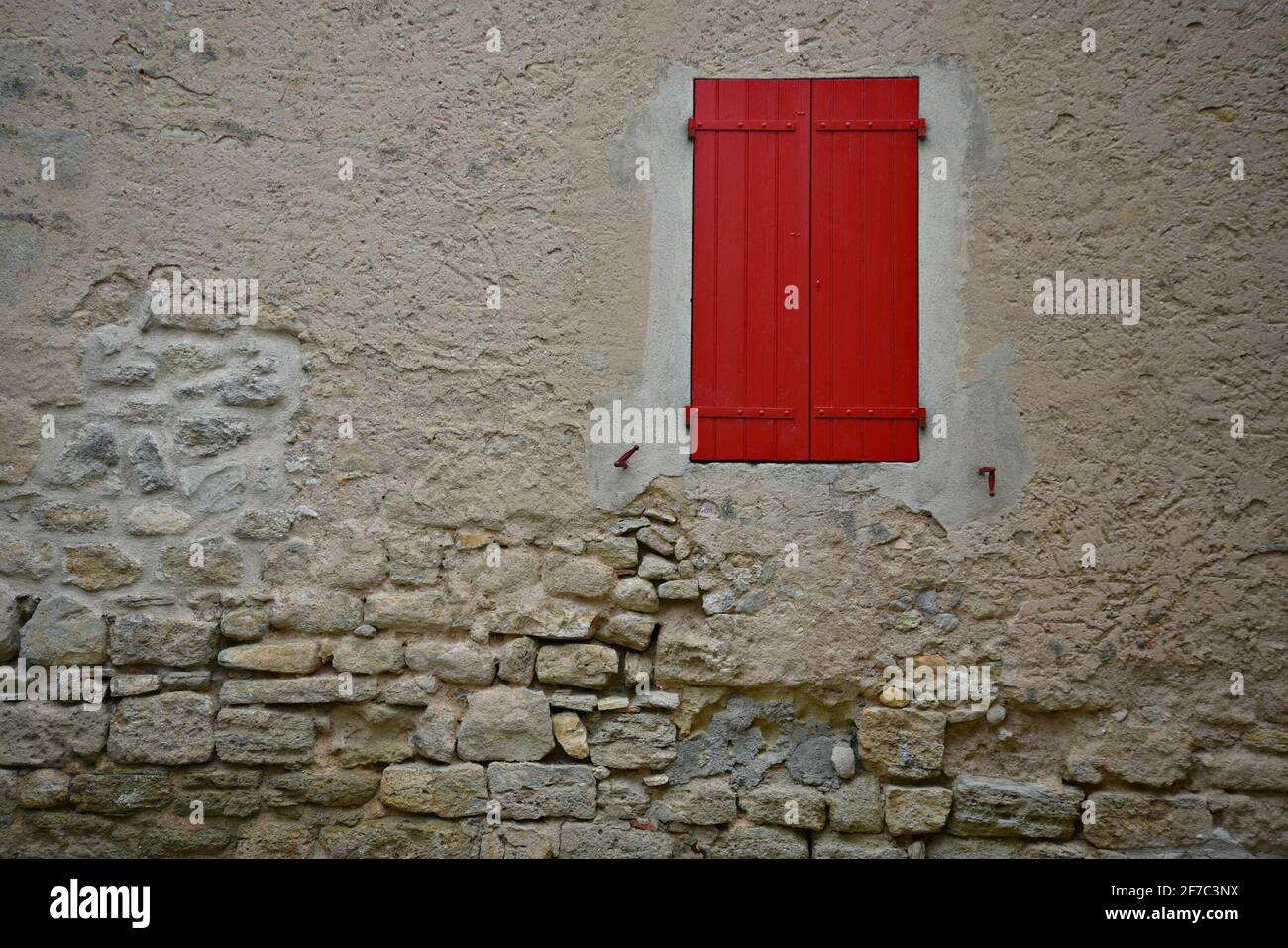 Rural Provençal style house stone facade with a red wooden window  in the picturesque village of Grambois, Provence-Alpes-Côte d'Azur, Vaucluse France Stock Photo