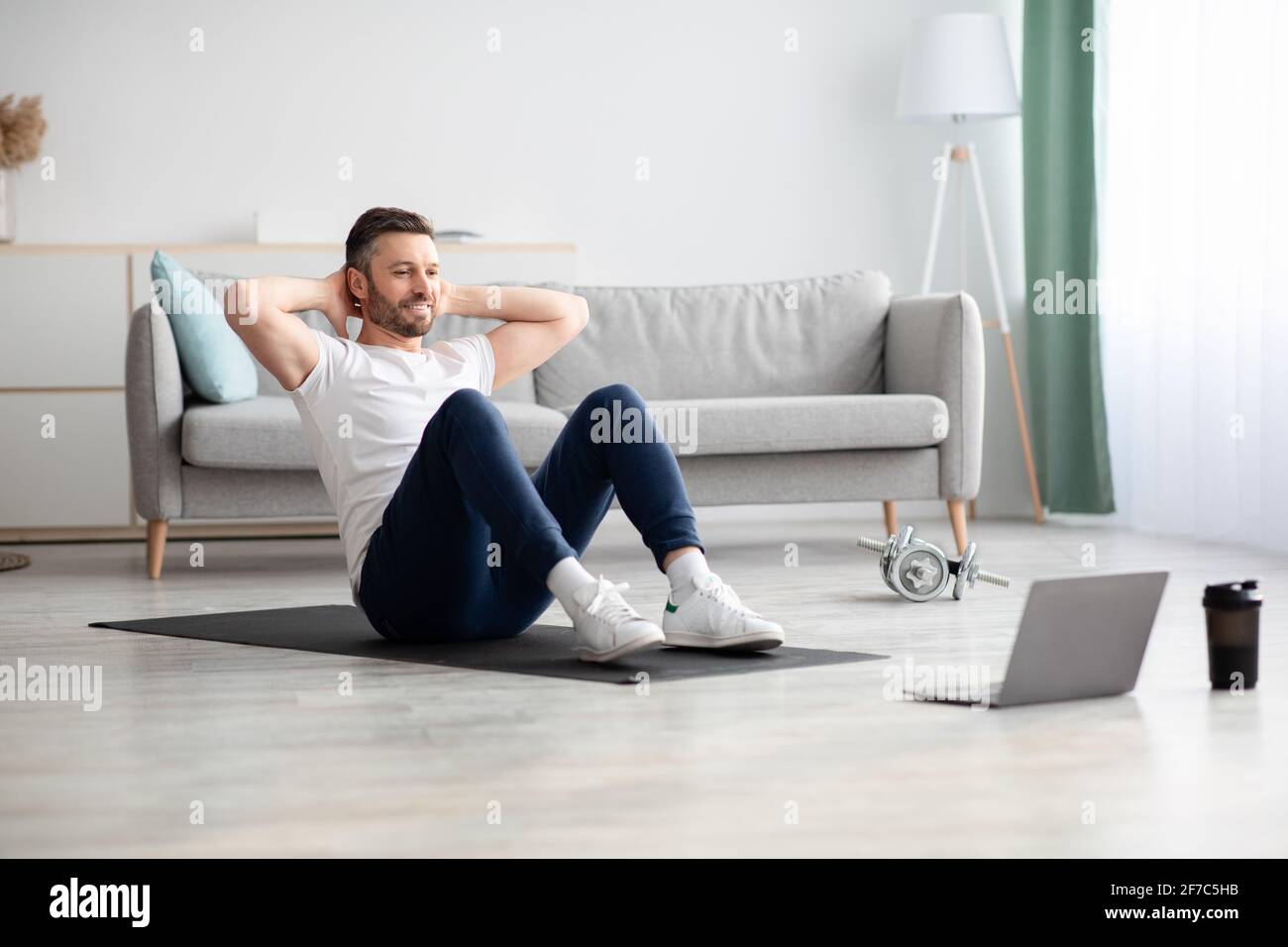 Smiling man working on abs, using laptop Stock Photo