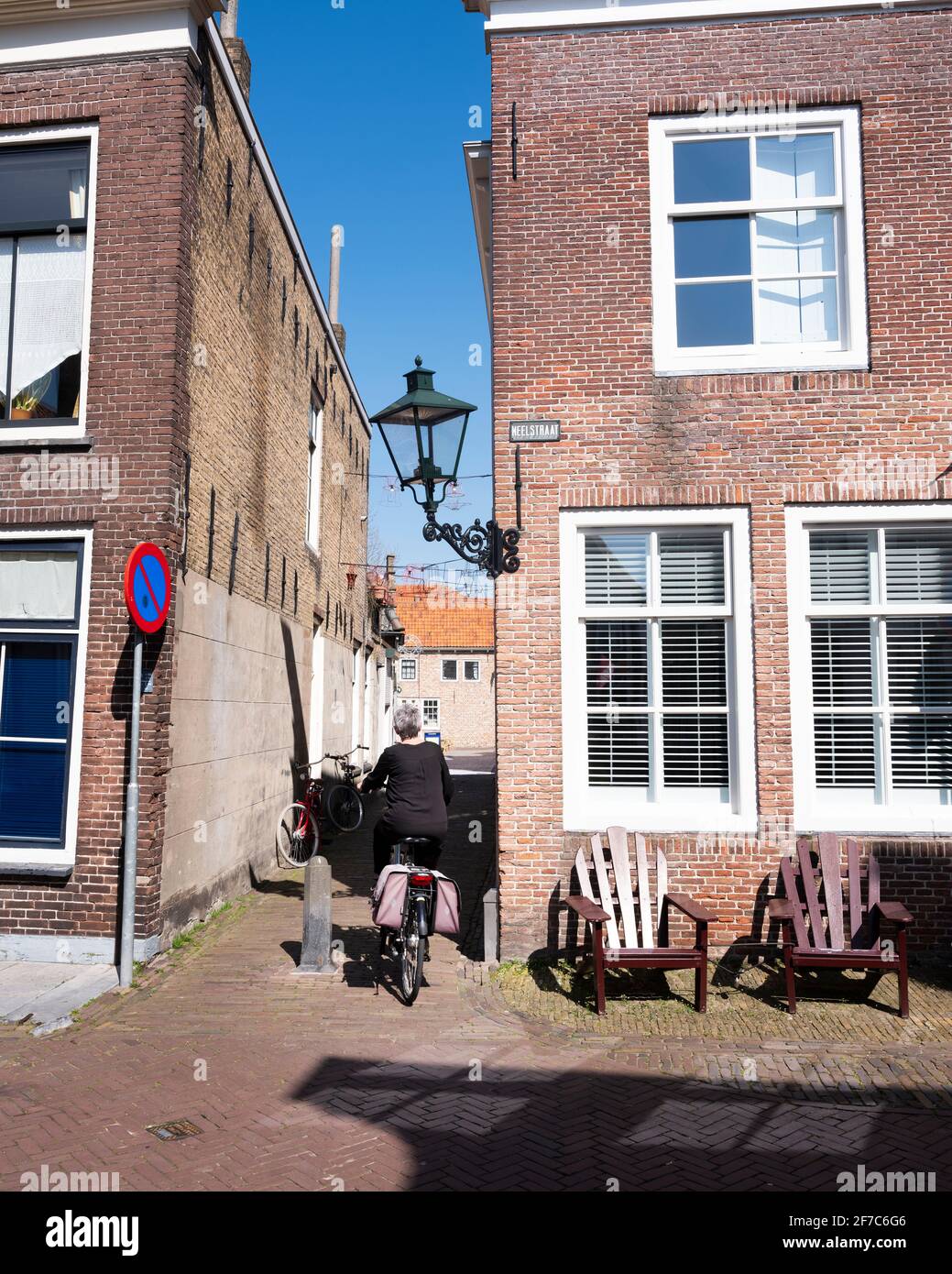 woman rides bicycle on old street in dutch town of zierikzee in spring Stock Photo