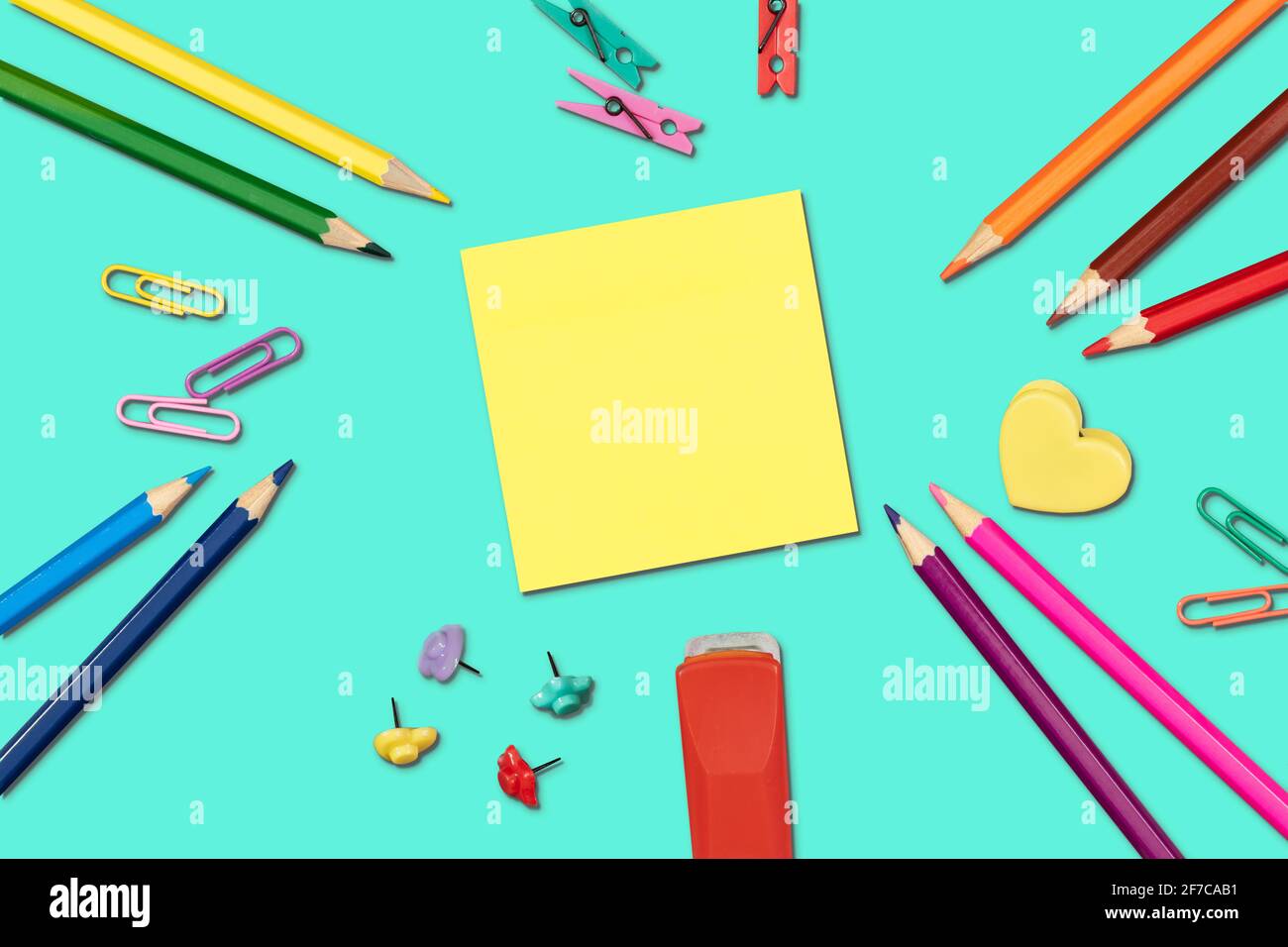 Bright back to school supplies with yellow sticky note on turquoise background. Flat lay. Stock Photo