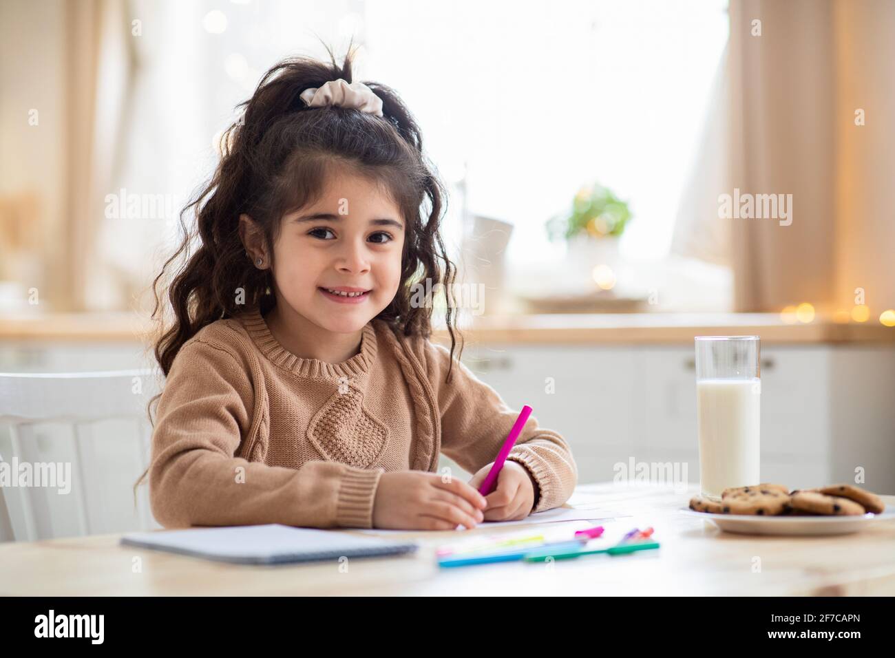 Children Development. Adorable Preschool Arab Girl Drawing In Kitchen At Home Stock Photo