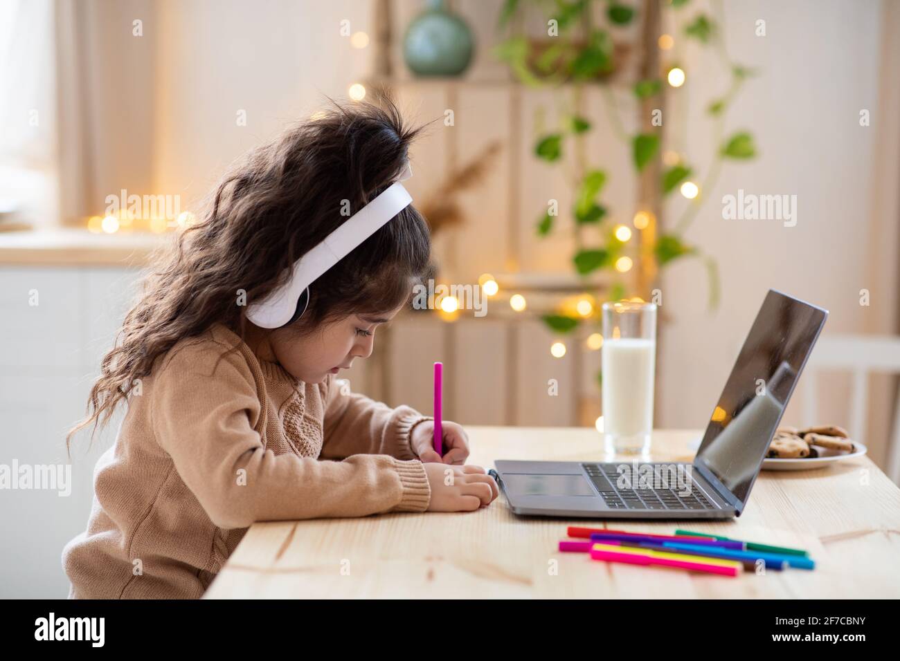 Cute Little Arab Girl In Headphones Study Online With Laptop In Kitchen Stock Photo Alamy