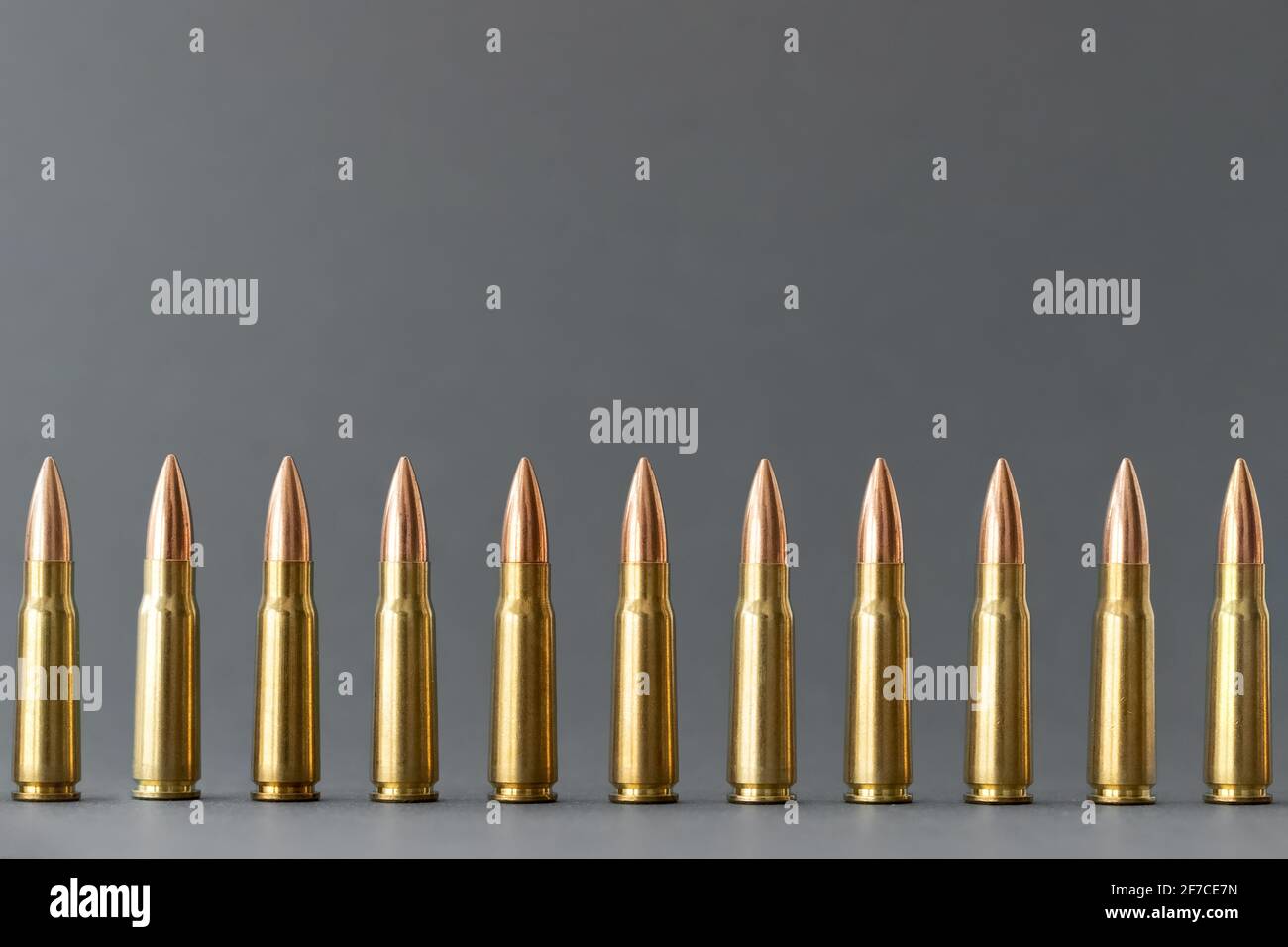 Bullets on gray background. Cartridges 7.62 caliber for Kalashnikov assault rifle closeup with copy space. Stock Photo