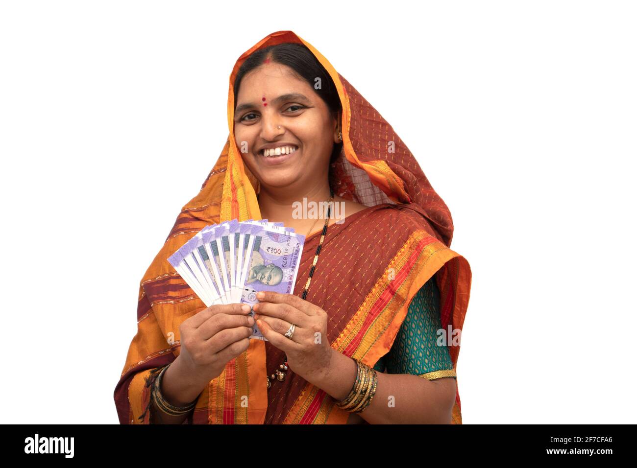 Happy smiling Indian woman holding Indian money or currency notes on isolated background - concept of woman empowerment, earnings, bank loan and Stock Photo