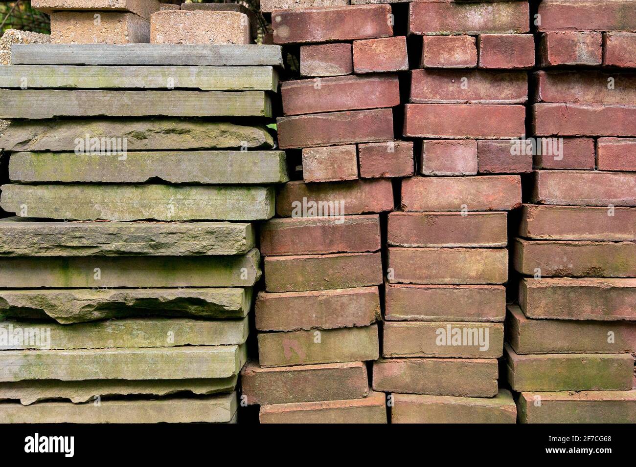 Brick blocks, slate slabs and other building materials are seen stacked on early springtime April day in moody, abstract, grunge background image Stock Photo