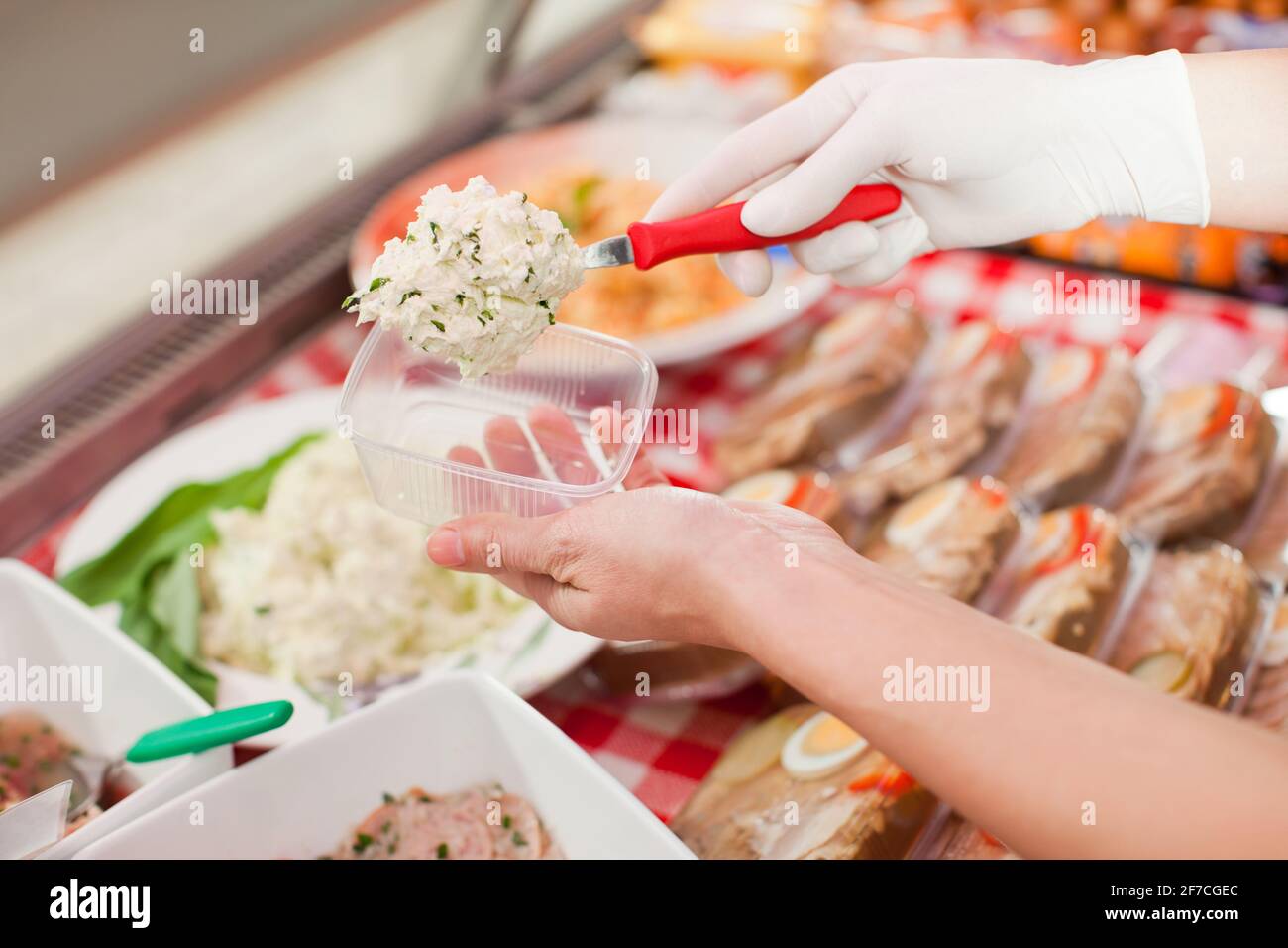 Working in a butchers shop - a shop assistant with curd cheese (only ...