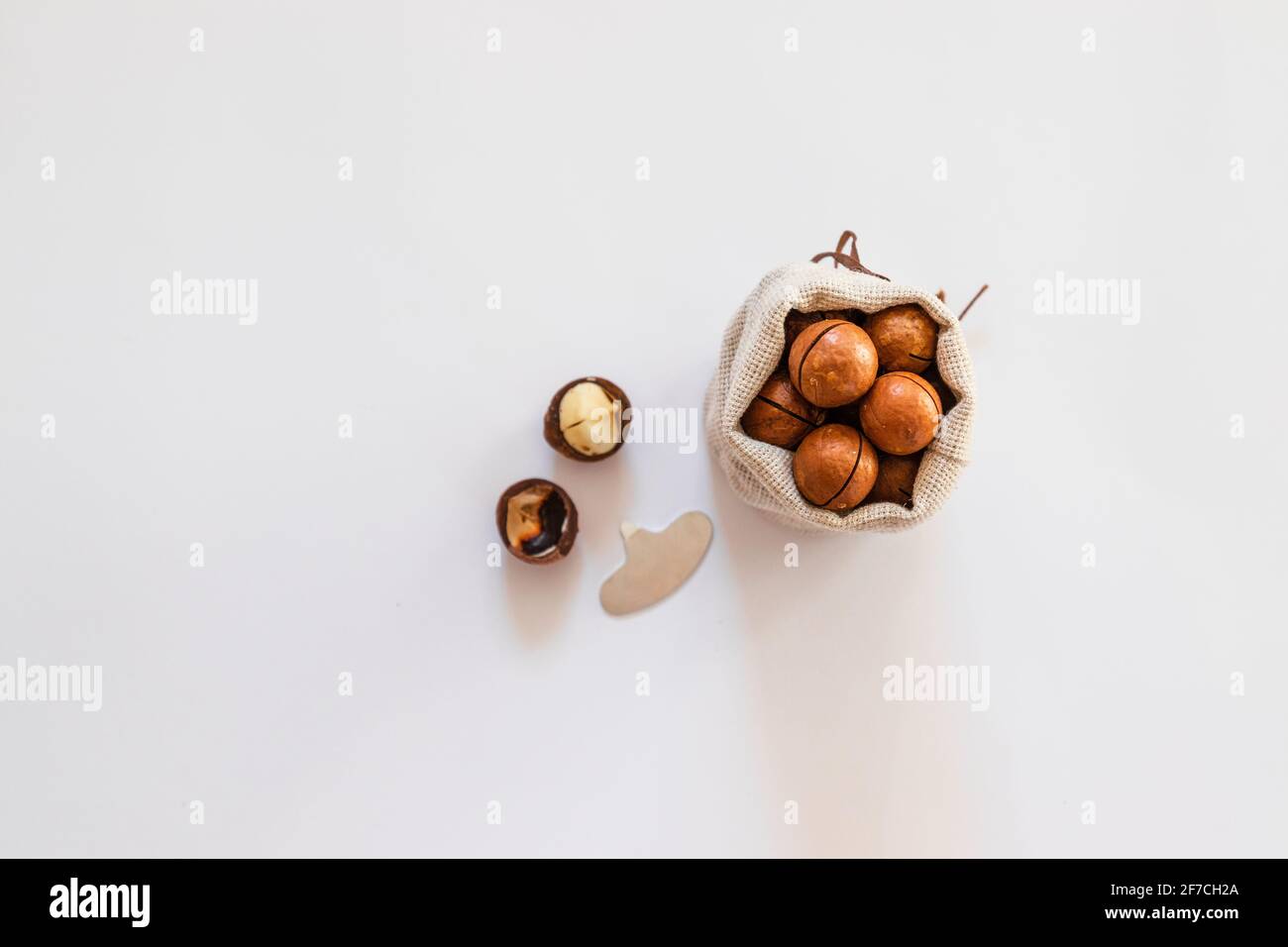 Raw macadamia nuts in canvas bowl on a white solid background. Minimal flat composition Stock Photo