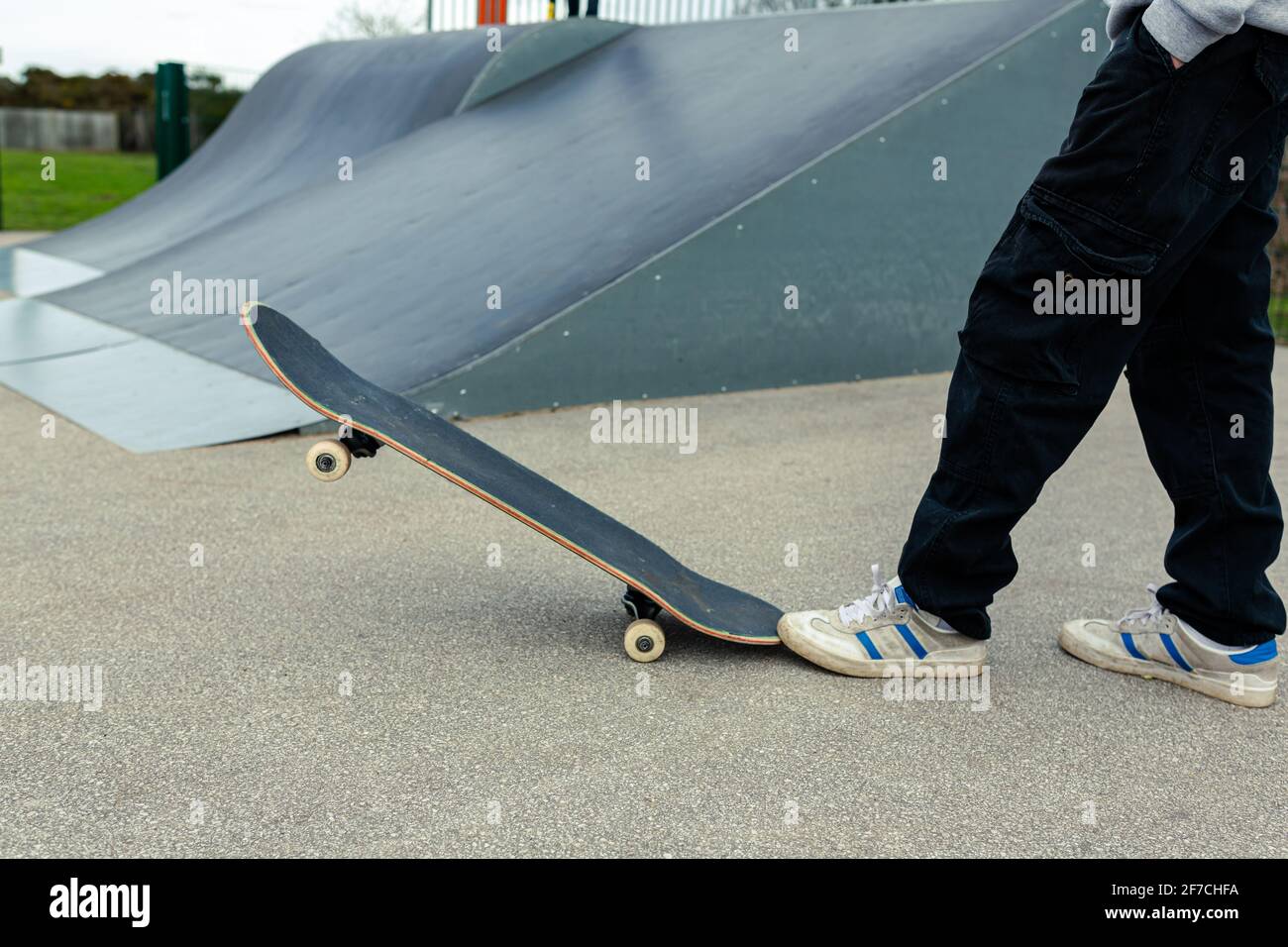 Close up of a skateboard with an unknown person standing behind it. Skateboarding healthy lifestyle concept Stock Photo