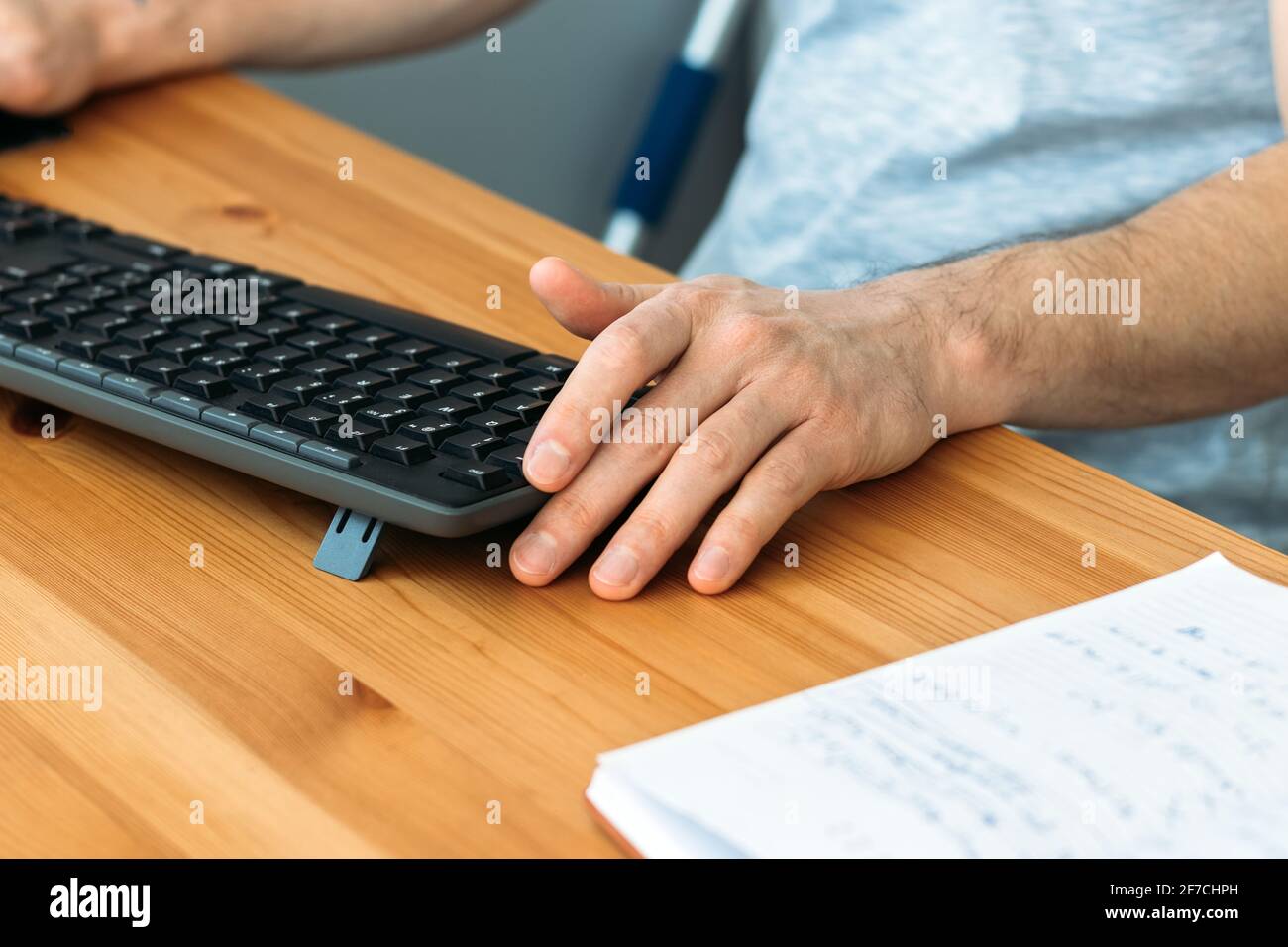 Wooden table with black wireless keyboard, male hands and a notebook. Selective focus Stock Photo
