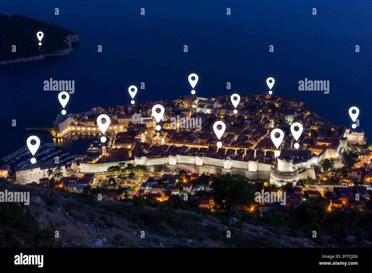 Map pin icons on Dubrovnik's cityscape at dusk. Walled Old Town of Dubrovnik in Croatia viewed from above at night. Stock Photo