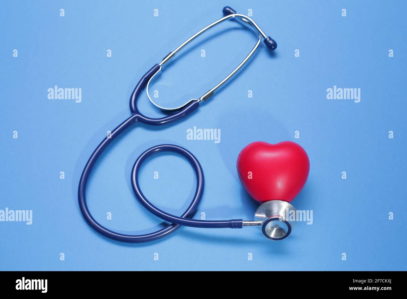 Red heart shape and stethoscope on blue background Stock Photo