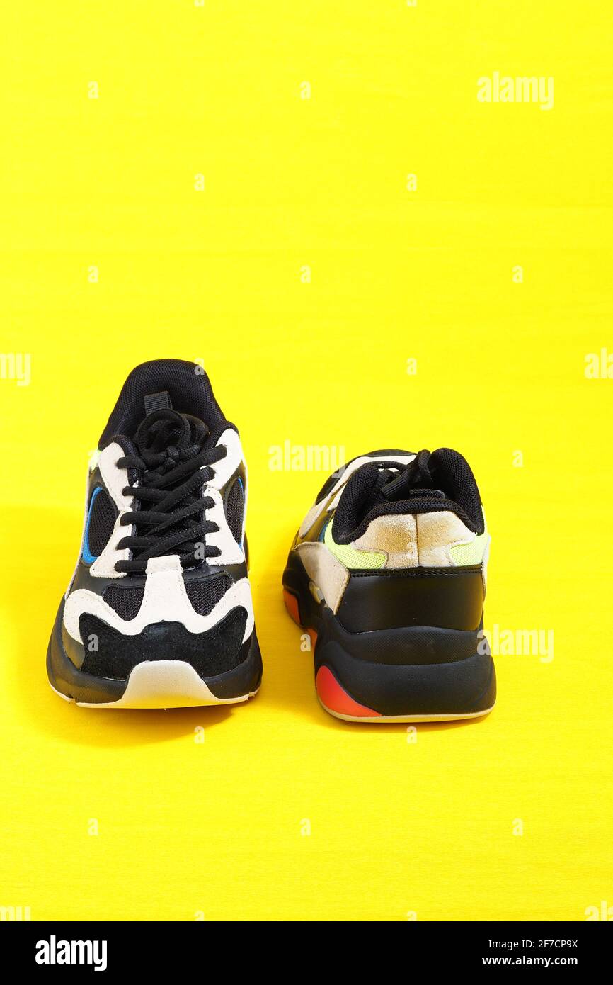 Sports shoes. Stylish fashionable sneakers on a yellow background. Vertical image. Stock Photo