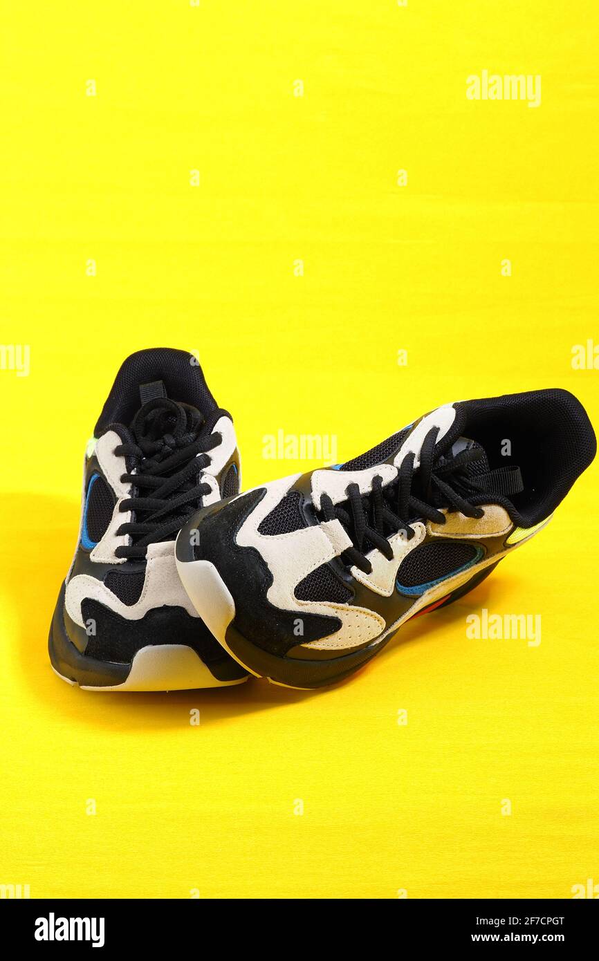 Sports shoes. Stylish fashionable sneakers on a yellow background. Vertical image. Stock Photo