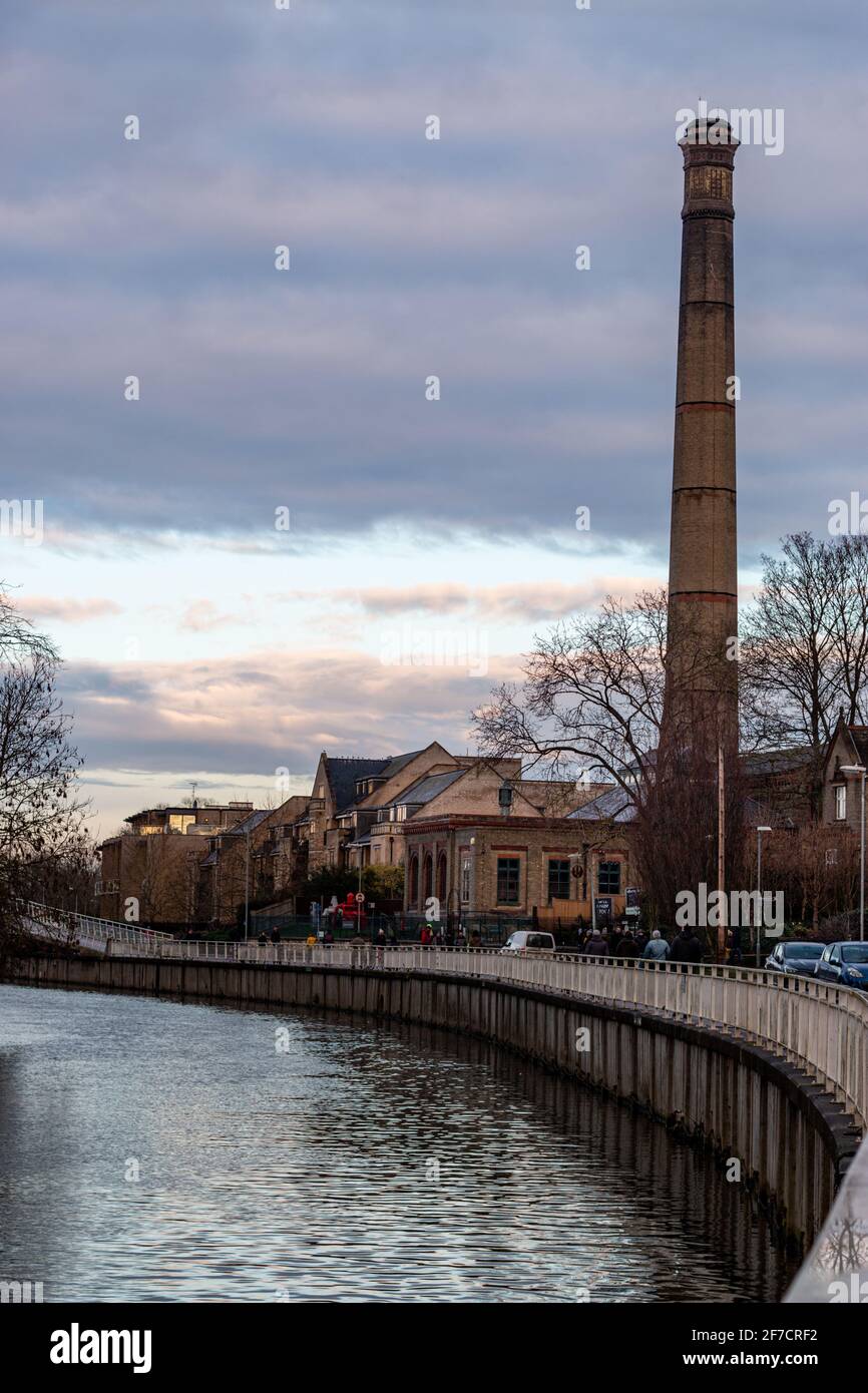 A view along the river Cam and the chimney of the old steam powered Victorian pumping station at the Cambridge Museum of Technology. UK Stock Photo