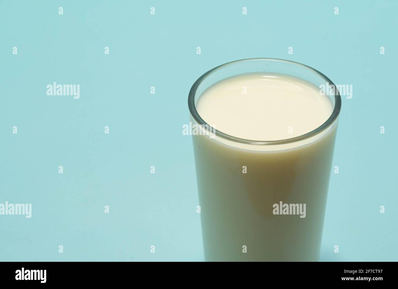 Glass cup served with milk on the blue background. Bone health food. Milk is one of the best sources of calcium available. Therefore, this food is ess Stock Photo